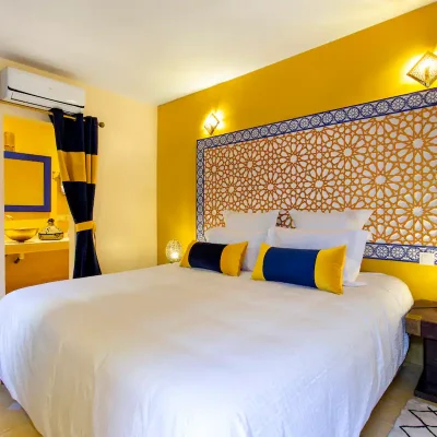 Chambre MAJORELLE Située au 1er étage, équipée d'un lit King size, décorée aux couleurs de la maison de Yves Saint Laurent, avec une tête de lit sculptée à la main par les artisans du derb, un sol assorti en carreaux ciment, et une salle de bain privée.